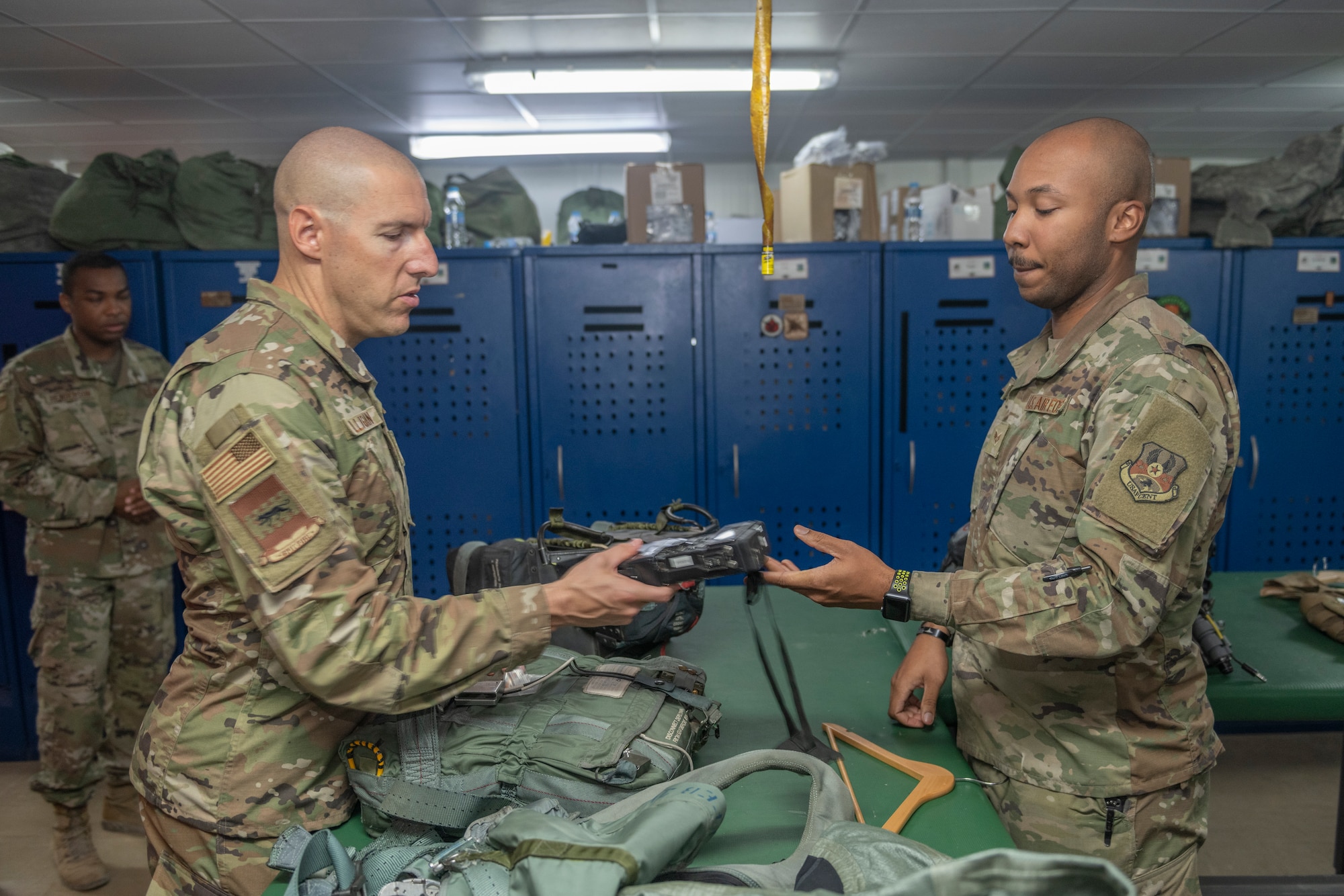 U.S. Air Force Senior Airman Rodney Tucker, right, 494th Expeditionary Fighter Squadron aircrew flight equipment technician, explains to Chief Master Sgt. Sean Milligan, 332nd Air Expeditionary Wing command chief, how to activate a Combat Survivor Evader Locator Sept. 4, 2021, at an undisclosed location somewhere in Southwest Asia. Aircrew flight equipment technicians ensure pilots are equipped with the specific gear needed to perform their missions. (U.S. Air Force photo by Senior Airman Cameron Otte)