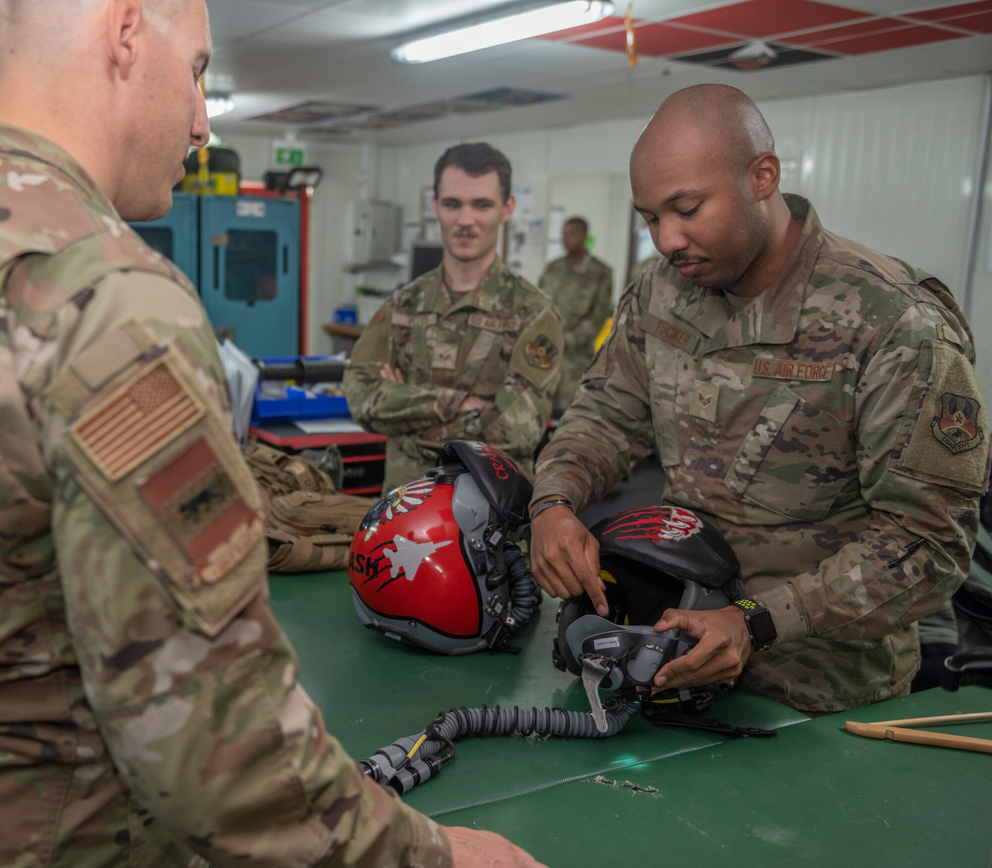 U.S. Air Force Senior Airman Rodney Tucker, right, 494th Expeditionary Fighter Squadron aircrew flight equipment technician, explains to Chief Master Sgt. Sean Milligan, 332nd Air Expeditionary Wing command chief, how a co-pilot dons their helmet Sept. 4, 2021, at an undisclosed location somewhere in Southwest Asia. Aircrew flight equipment technicians ensure pilots are equipped with the specific gear needed to perform their missions. (U.S. Air Force photo by Senior Airman Cameron Otte)