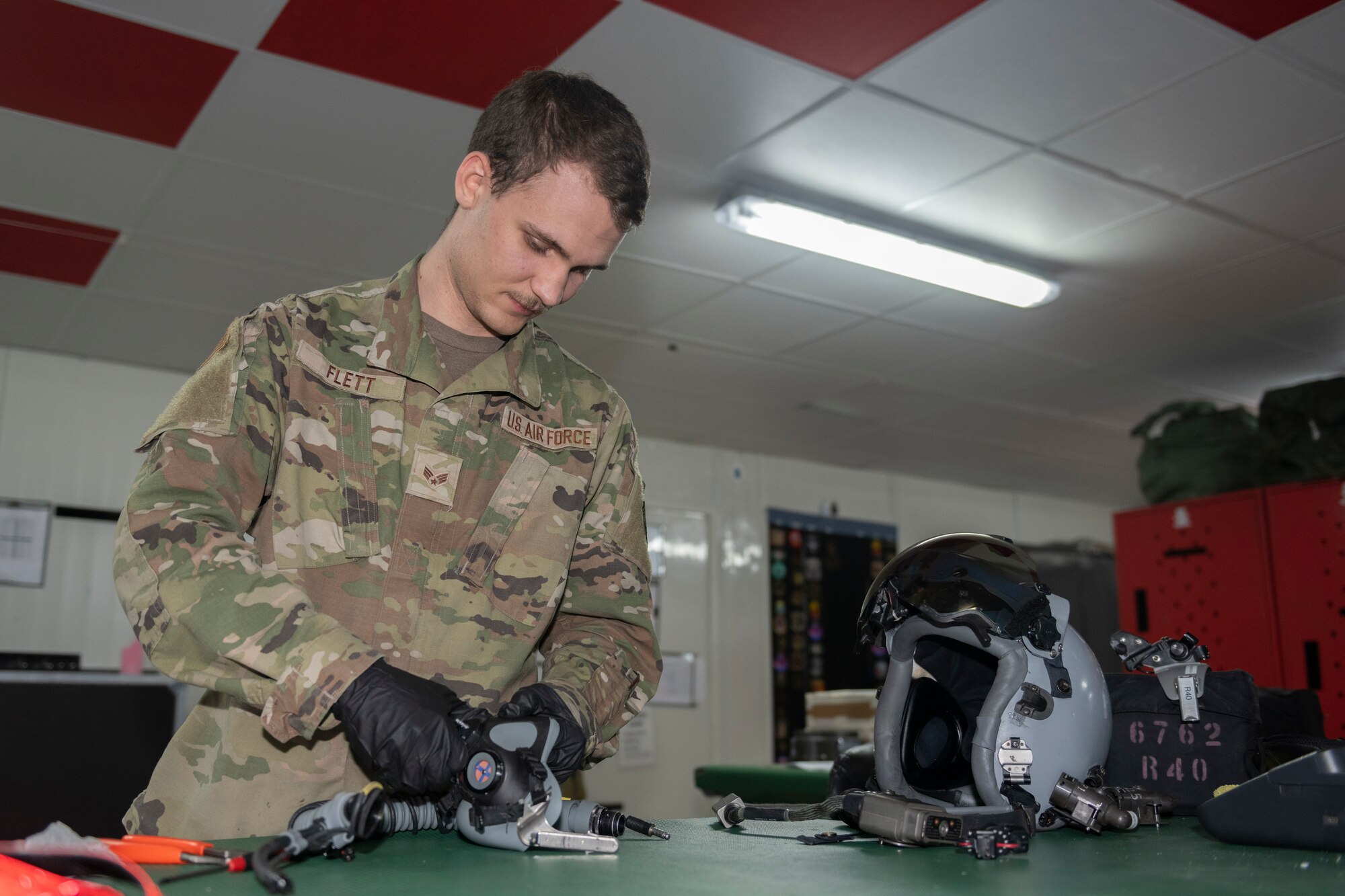 U.S. Air Force Senior Airman Jesse Flett, 494th Expeditionary Fighter Squadron aircrew flight equipment technician, inspects a helmet for damages Sept. 7, 2021, at an undisclosed location somewhere in Southwest Asia. Aircrew flight equipment technicians ensure pilots are equipped with the specific gear needed to perform their missions. (U.S. Air Force photo by Senior Airman Cameron Otte)