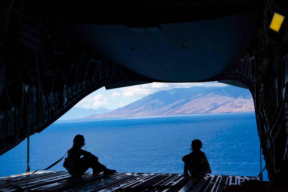 Two airmen sit on the ramp of an aerial aircraft.