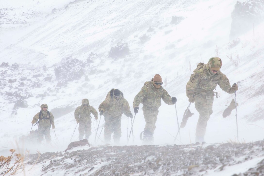 Soldiers cross-country sky through snow.