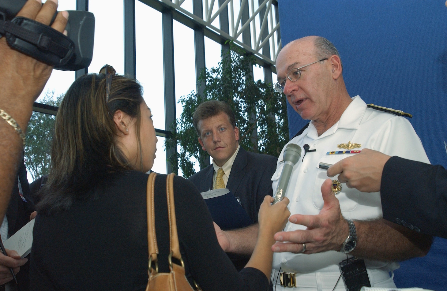 Female reporter holding microphone with cameraman behind her, asking Chief of naval operations questions during an interview