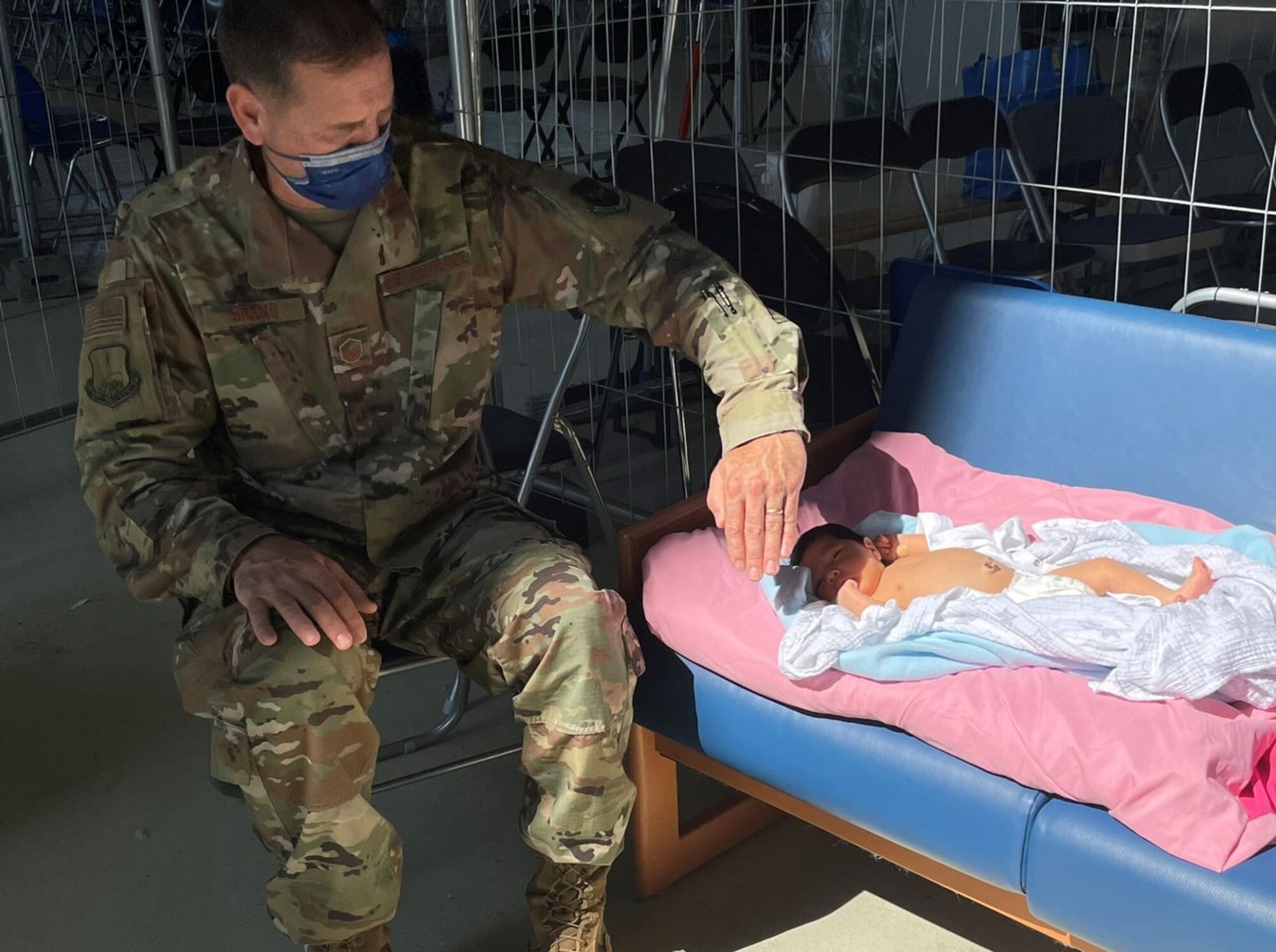 U.S. Air Force Master Sgt. Steve Brooks, 117th Air Refueling Wing religious affairs airman, shields a three-day-old baby's eyes from the sun September 3, 2021, at Ramstein Air Base, Germany. The baby, born to Afghan evacuee parents at Landstuhl Regional Medical Center, received phototherapy for a case of jaundice at the 521st Air Mobility Operations Wing’s Hangar 5 prior to boarding a flight. Brooks is a Religious Affairs Airman from the Alabama National Guard serving at Ramstein Air Base, Germany in support of Operation Allies Refuge. (U.S. Air Force courtesy photo)