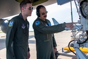 two people stand underneath aircraft
