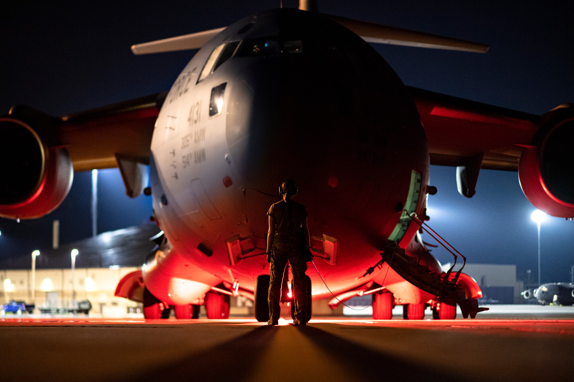 Photo of an Airman standing in front of an aircraft at night