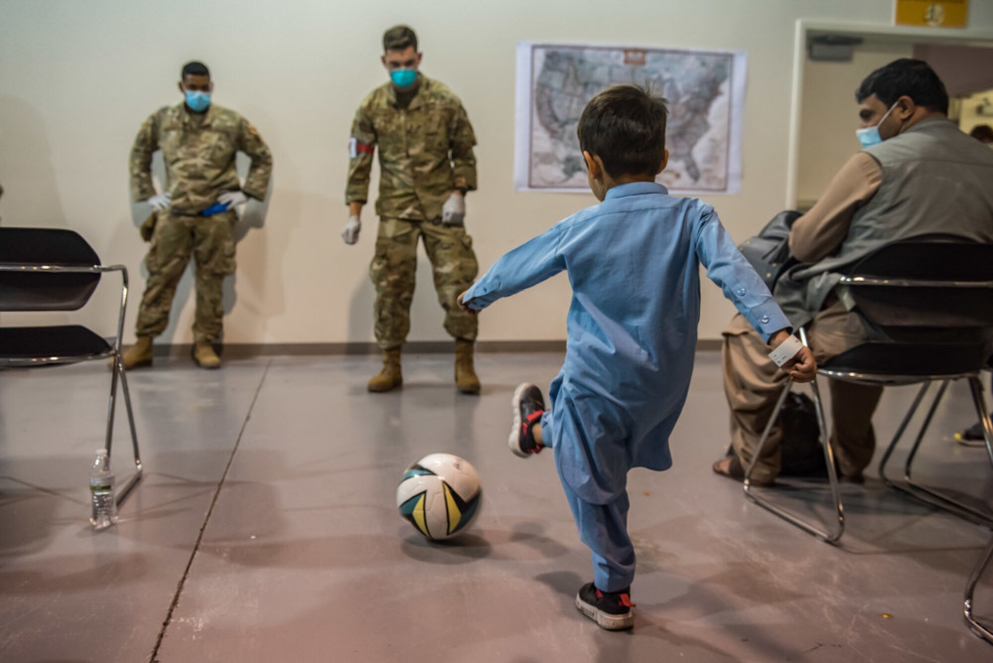 An Airman from Task Force-Holloman plays soccer with an Afghan evacuee at Holloman Air Force Base, New Mexico, Aug. 31, 2021. The Department of Defense, through U.S. Northern Command, and in support of the Department of State and Department of Homeland Security, is providing transportation, temporary housing, medical screening, and general support for up to 50,000 Afghan evacuees at suitable facilities, in permanent or temporary structures, as quickly as possible. This initiative provides Afghan evacuees essential support at secure locations outside Afghanistan. (U.S. Air Force photo by Staff Sgt. Kenneth Boyton)