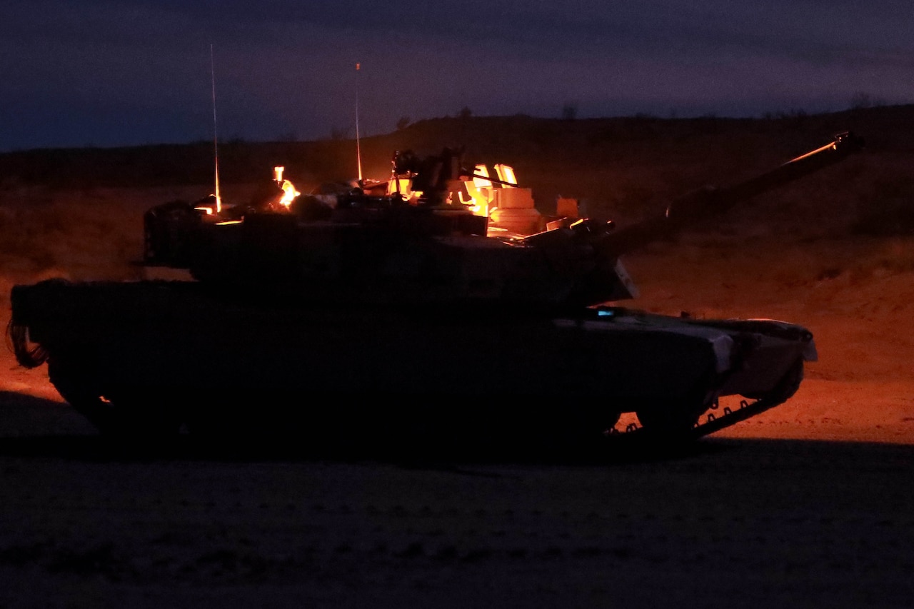 A tank sits on a range at night.