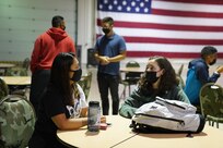 Spc. Elvira Zapada (left) and Pfc. Taylor Sperry, from 1st Battalion, 297th Infantry Regiment, Alaska Army National Guard, wait on the drill hall floor of the Joint Base Elmendorf-Richardson National Guard armory, Sept. 3, 2021, for transportation to the airport. They departed that evening for Louisiana. 17 Alaska Guardsmen will assist the Louisiana National Guard's support to civil authorities in the aftermath of Hurricane Ida, which struck the state Aug. 29, leaving disaster, destruction and flooding in its wake. (By U.S. Air National Guard Lt. Col. Candis Olmstead)