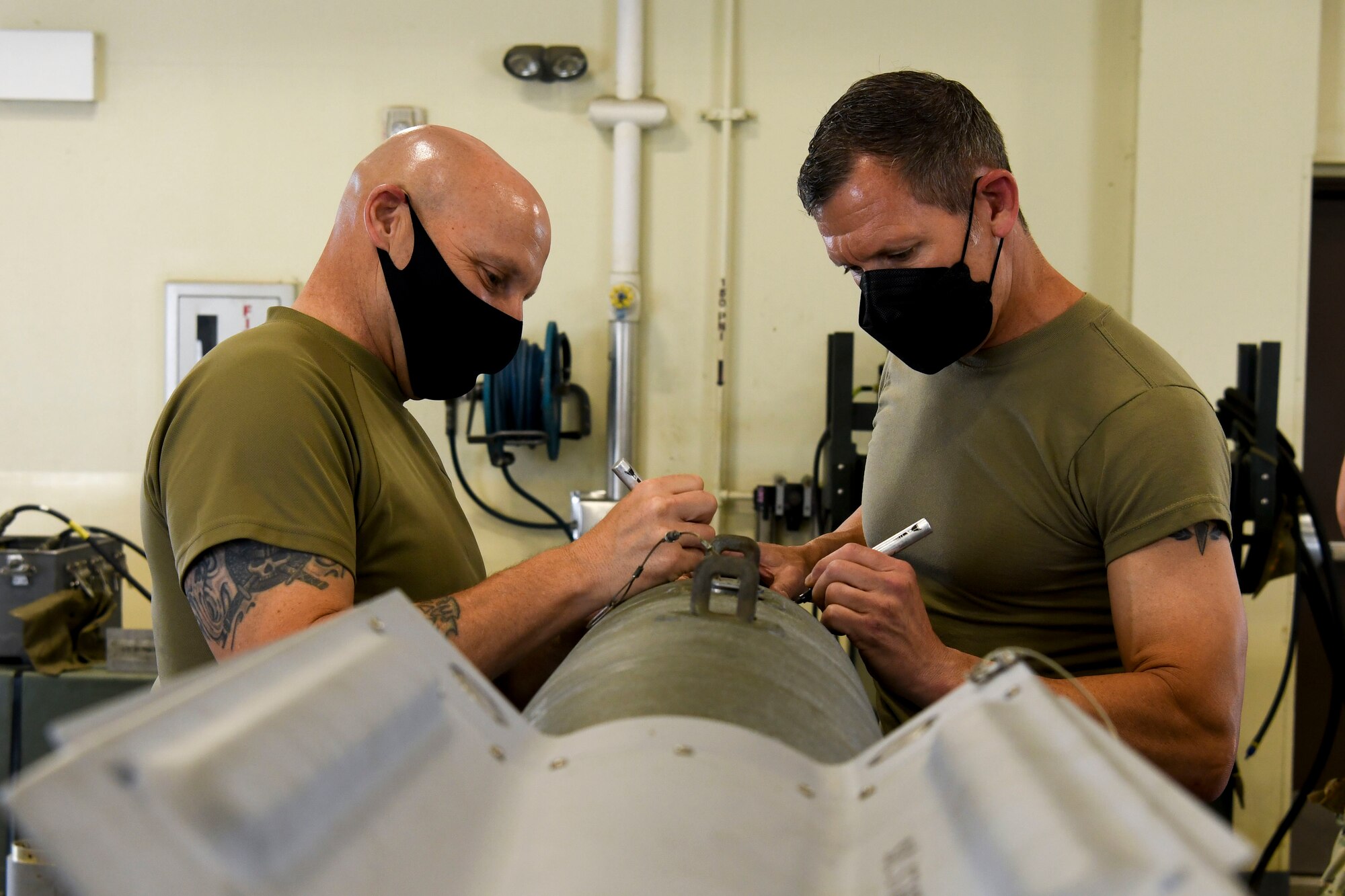 Two Airmen sign a munition.