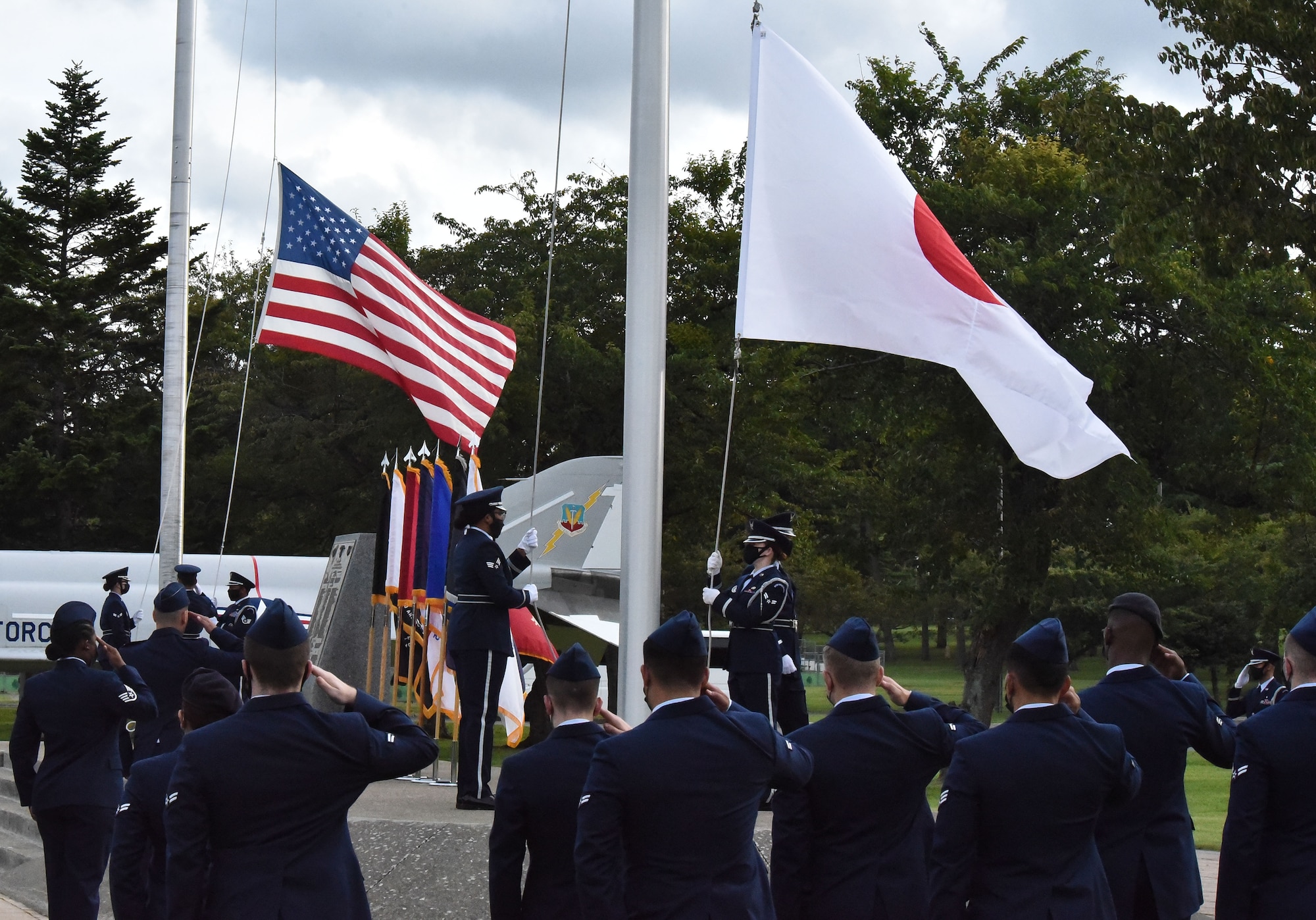 Military members salute the Japanese and U.S. flag as they are being lowered by the honor guard.