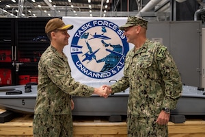 Vice Adm. Brad Cooper, left, commander of U.S. Naval Forces Central Command, U.S. 5th Fleet and Combined Maritime Forces, shakes hands with Capt. Michael D. Brasseur, the first commodore of Task Force (TF 59) during a commissioning ceremony for TF 59 onboard Naval Support Activity Bahrain, Sept. 9. TF 59 is the first U.S. Navy task force of its kind, designed to rapidly integrate unmanned systems and artificial intelligence with maritime operations in the U.S. 5th Fleet area of operations.