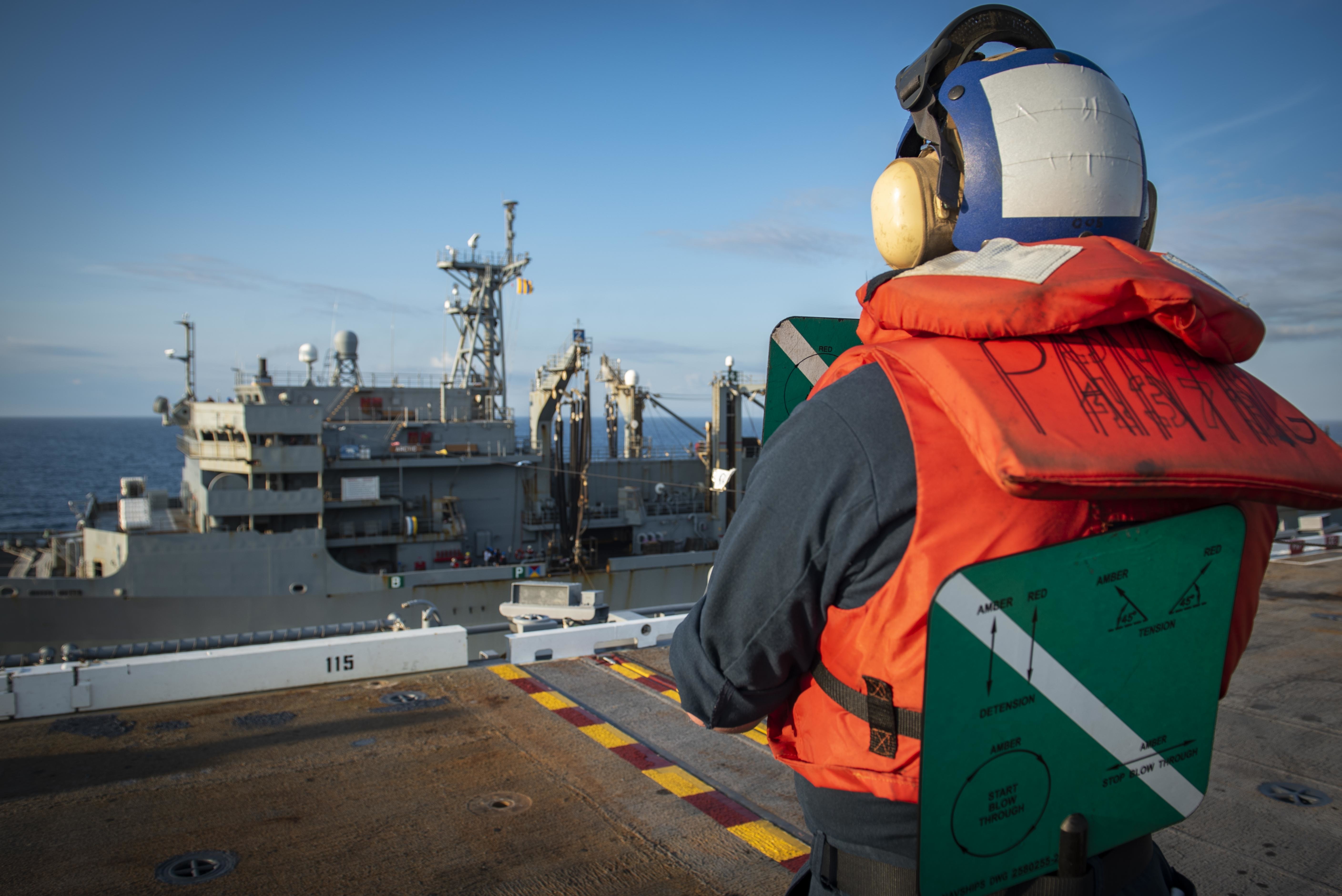 Seaman Matthew Kortie, assigned to the Deck Department of the aircraft carrier USS George H.W. Bush (CVN 77), stands signalman watch as GHWB pulls alongside fast combat support ship USNS Arctic (T-AOE 8) for a replenishment-at-sea.