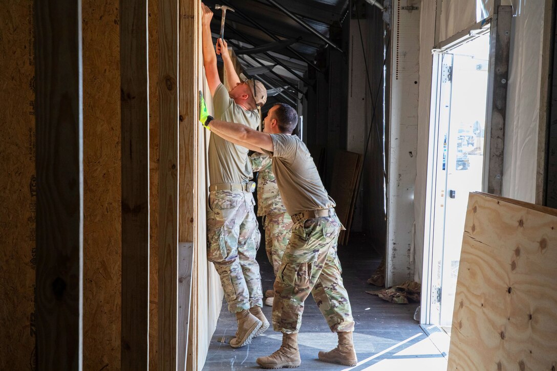 Airmen put up wood for walls.