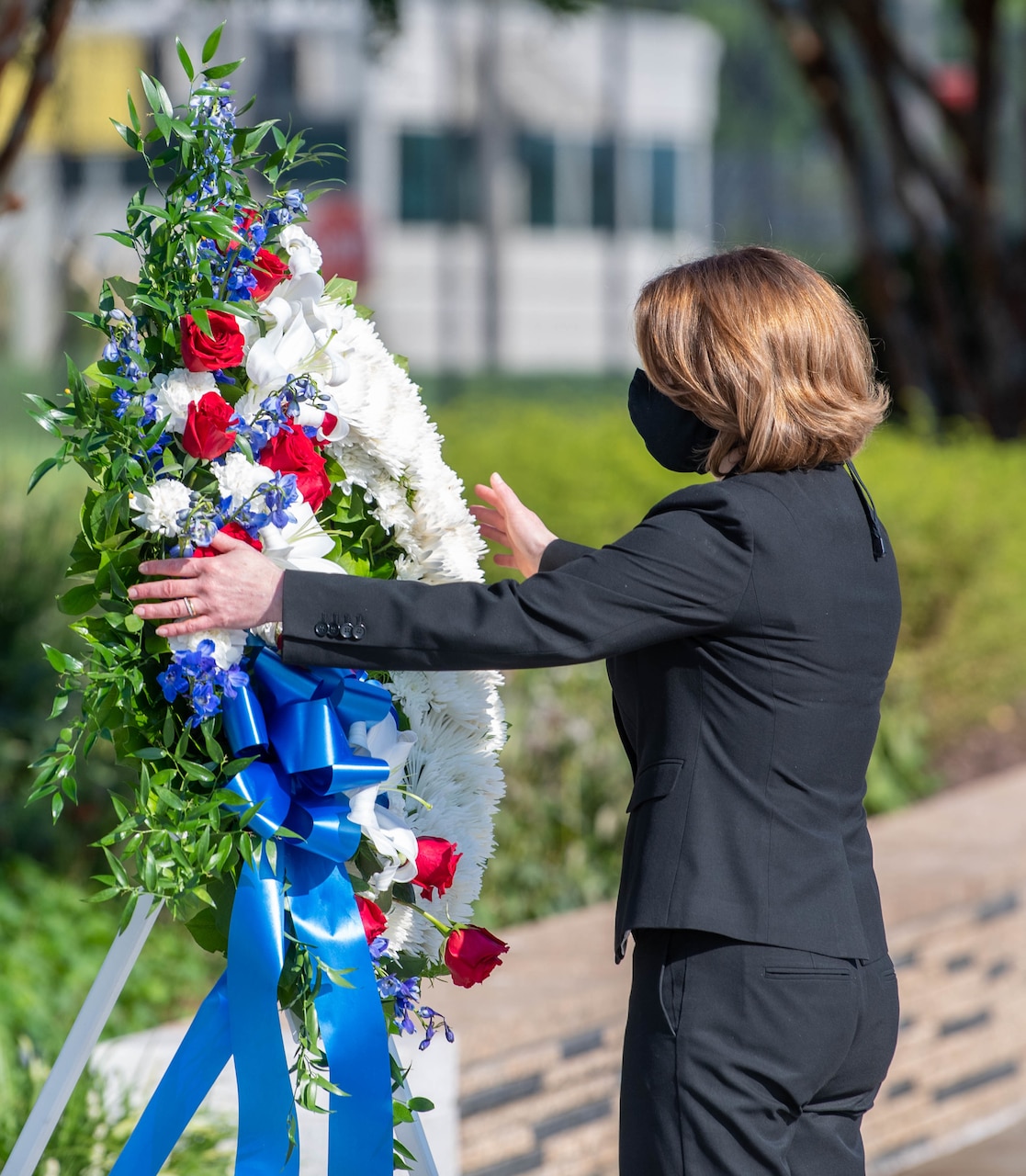 A woman lays a wreath at a memorial.