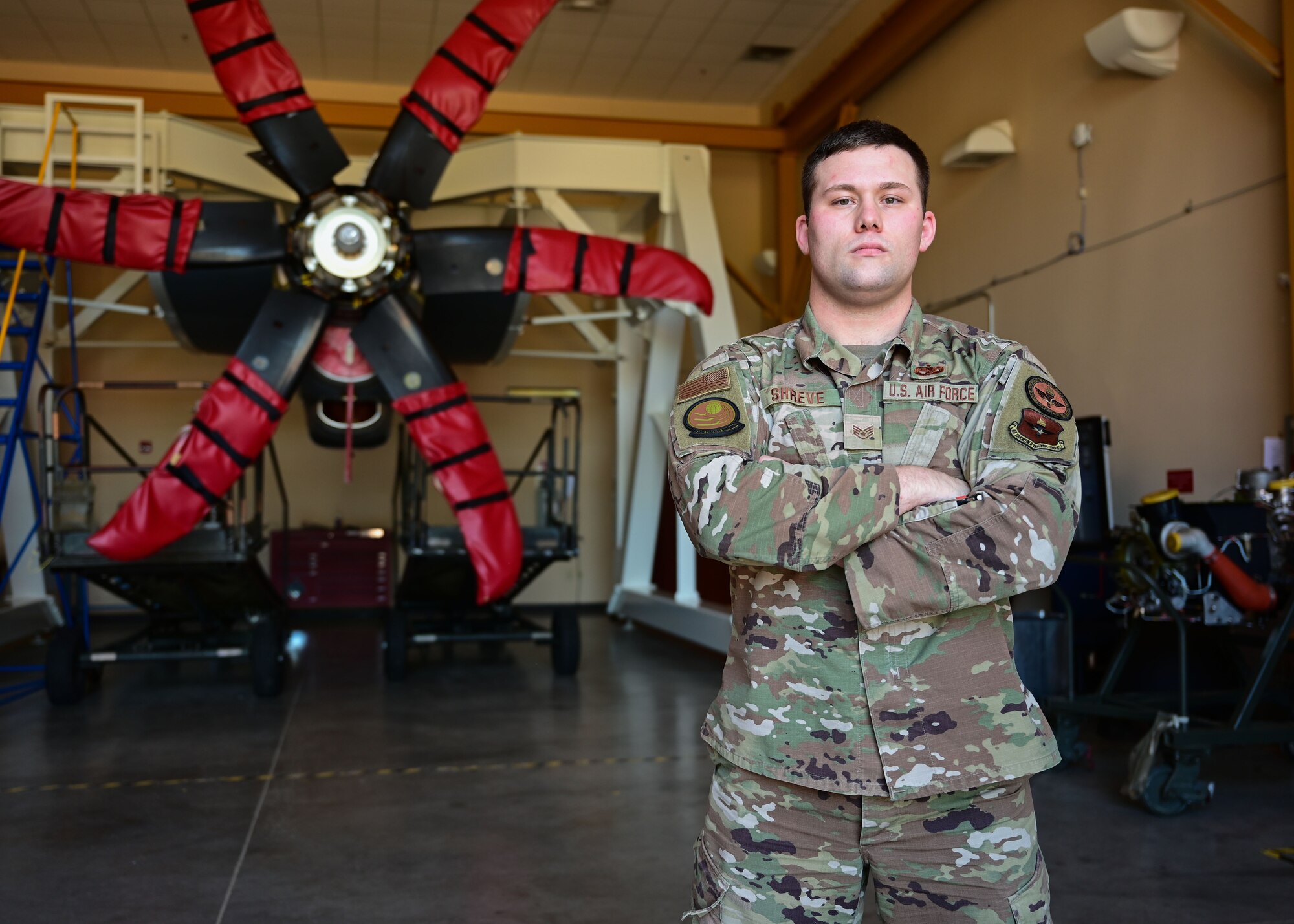 An Airman stands in front of a C-130J's engine.