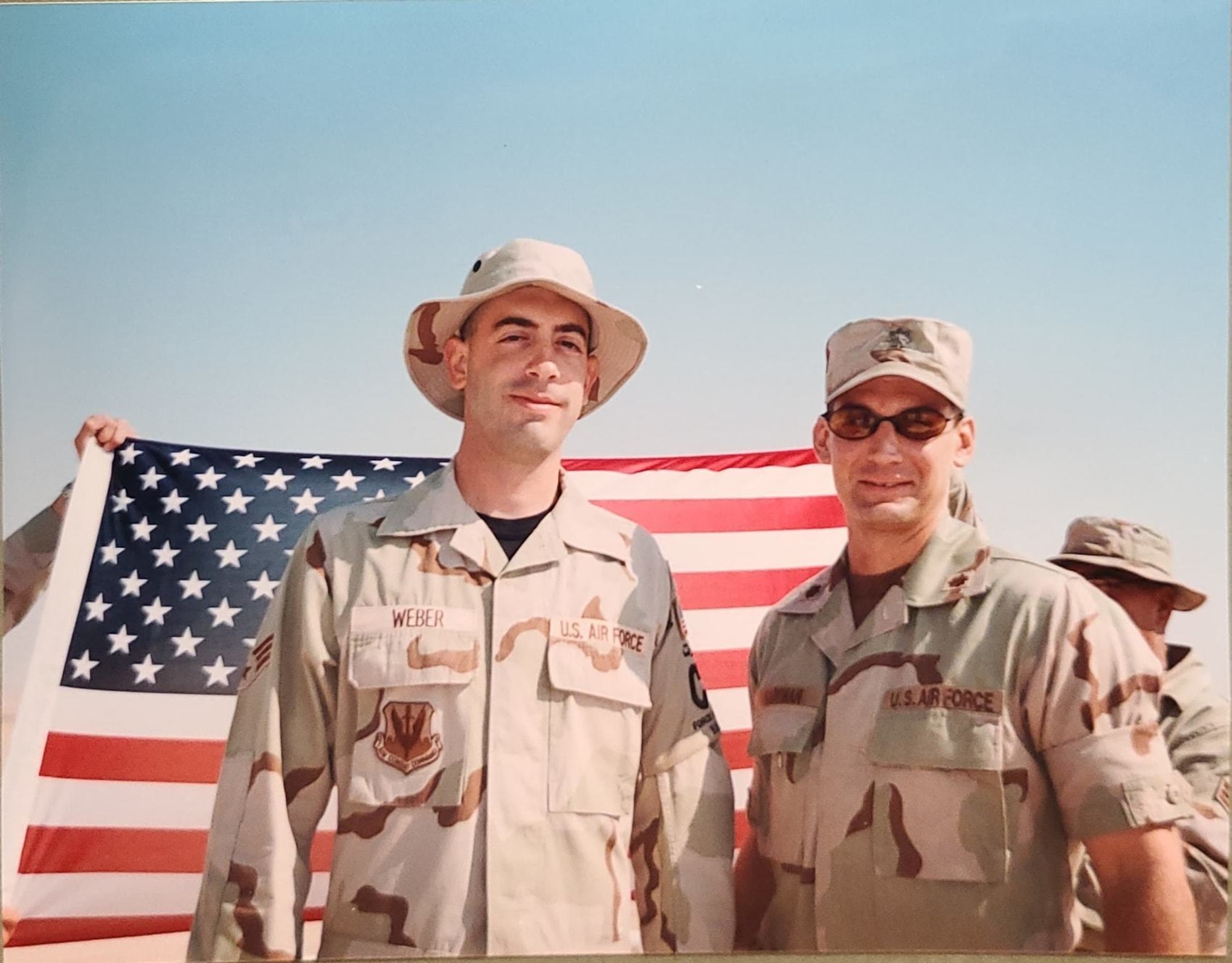 Then Senior Airman Mark Weber, left, 378th Expeditionary Civil Engineer Squadron force protection member, poses for a photo after reenlisting at Prince Sultan Air Base, Kingdom of Saudi Arabia in 2002. Following the 9/11 attacks, deployments increased, including for Weber, who deployed outside his career field in support of the global war on terrorism. (Courtesy Photo)