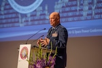 A military officer speaks from behind a podium.