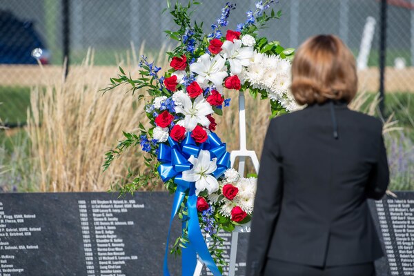 A woman lays a wreath at a memorial.