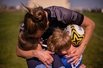 U.S. Air Force Staff Sgt. Stefani Loisel, 60th Surgical Services Squadron aerospace medical technician, hugs her sons, Noah, left, and Kaden Aug. 11, 2021, at Travis Air Force Base, California. Loisel contributes to the recruitment, retention and readiness of service members by playing on the USAF Women’s Rugby Team, which is a part of Armed Forces Sports. After her more than two years of training to be on and finally joining the USAF Rugby Team came to a halt due to the pandemic, the team played in the June 2021 Annual Armed Forces Women’s Rugby Championship in Wilmington, North Carolina, securing second place. (U.S. Air Force photo by Nicholas Pilch)