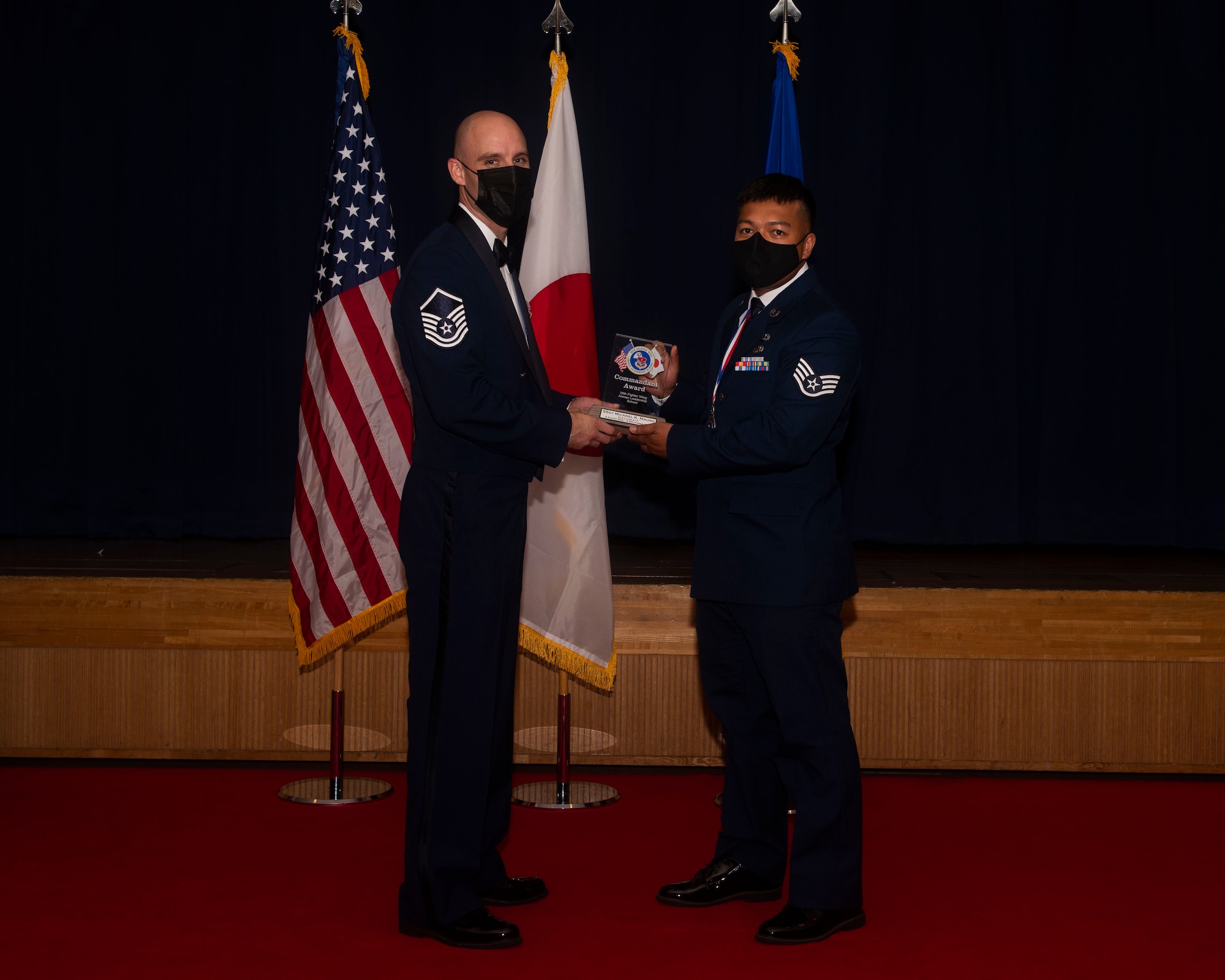 Military members in uniform pose with an award for a photo