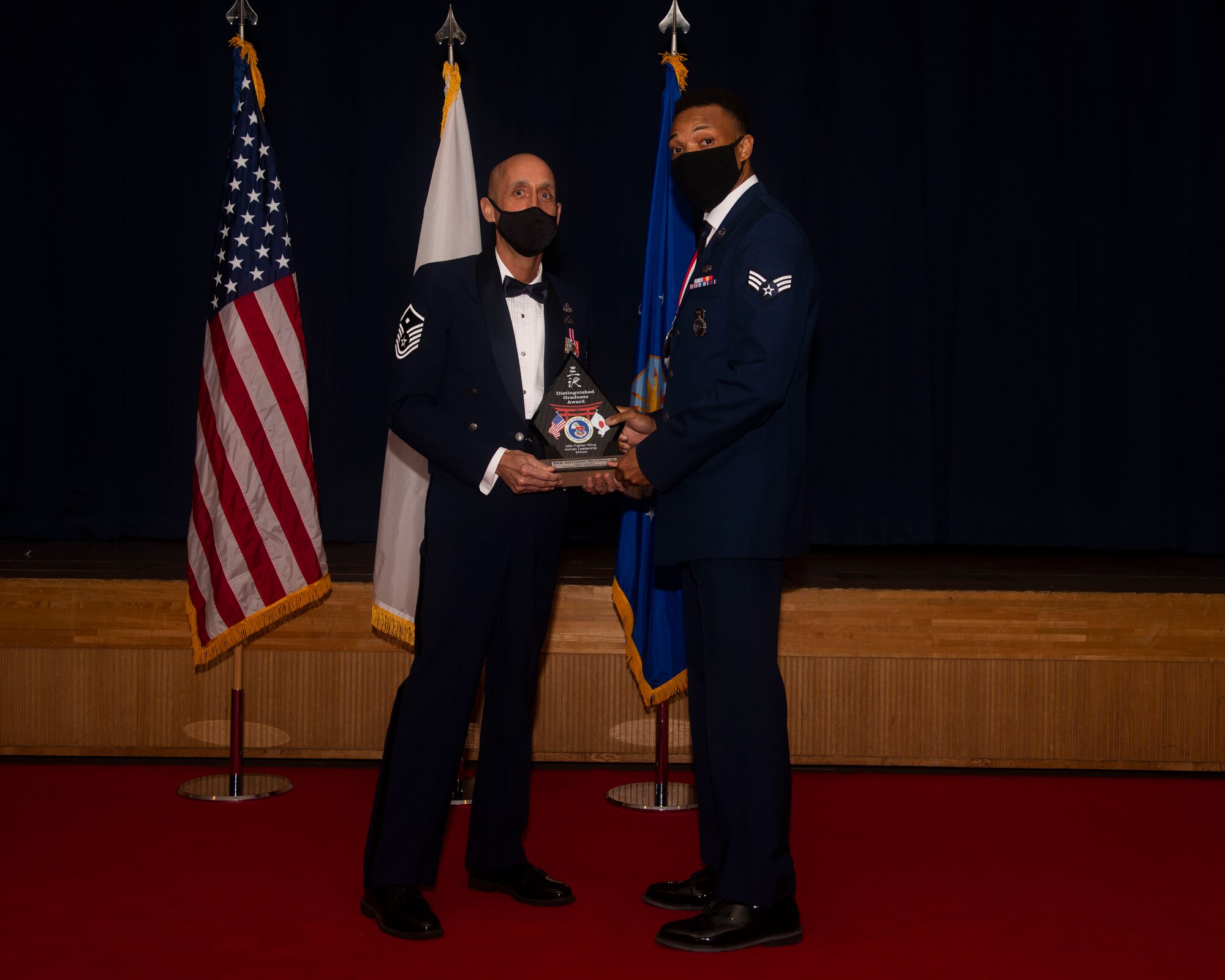 Military members in uniform pose with an award for a photo