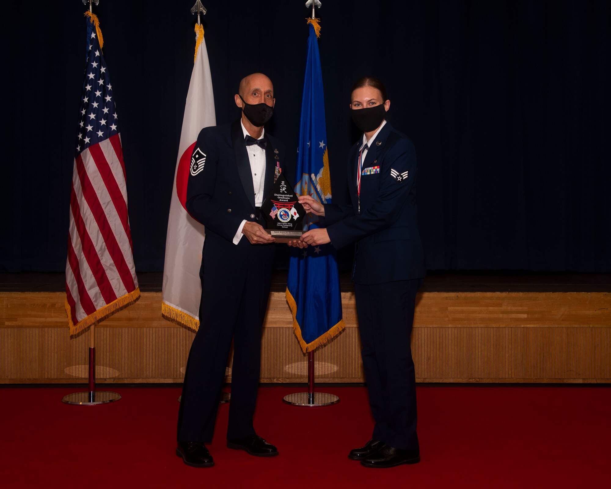 Military members in uniform pose with an award for a photo