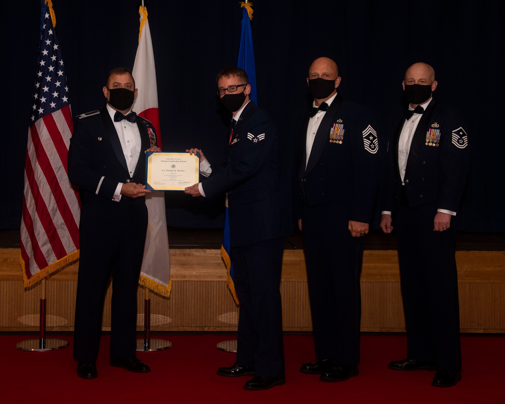 Military members in uniform pose with a diploma for a photo