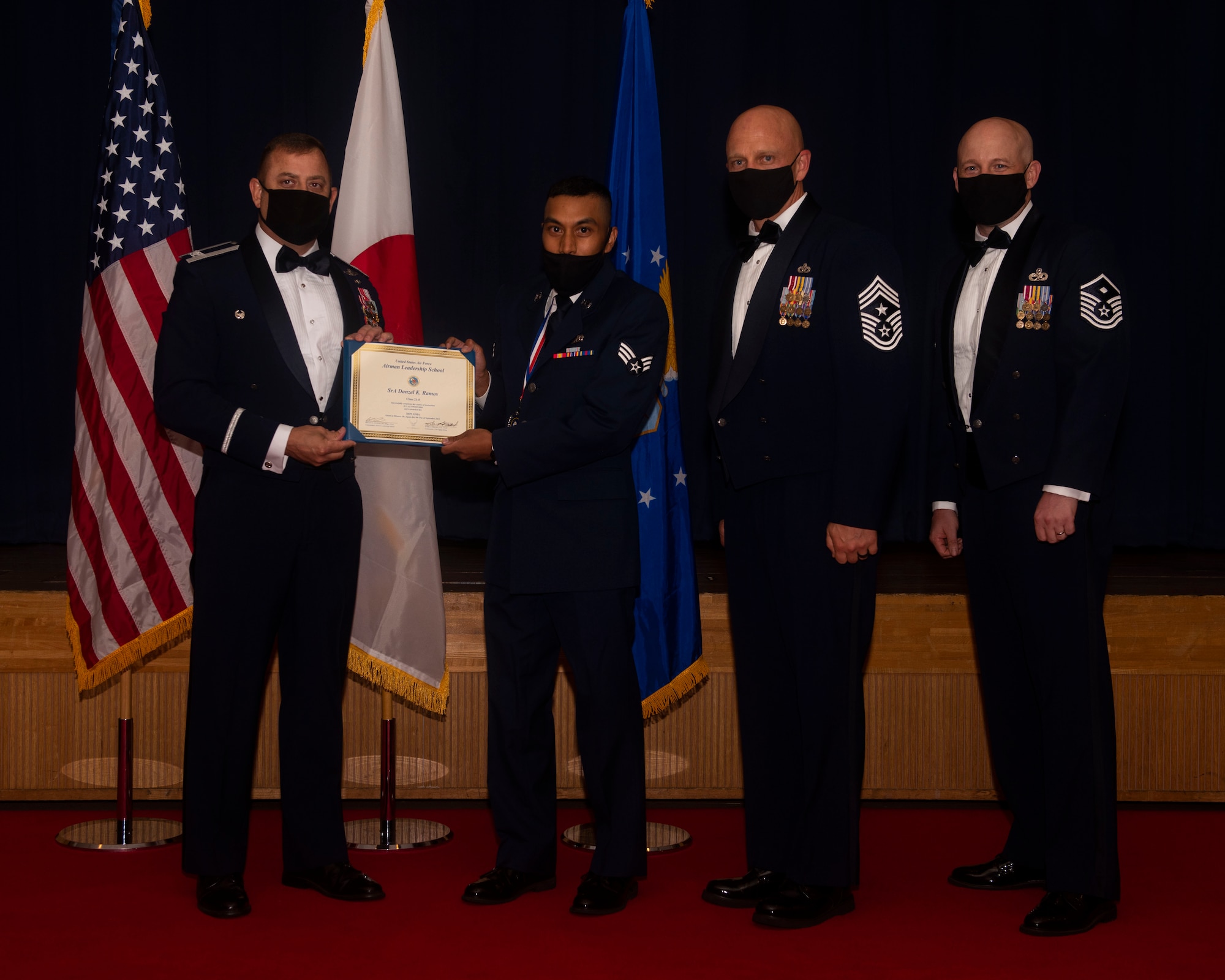 Military members in uniform pose with a diploma for a photo