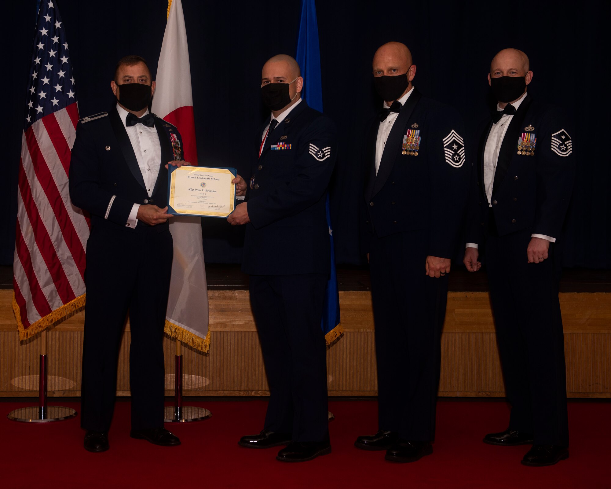 Military members in uniform pose with a diploma for a photo