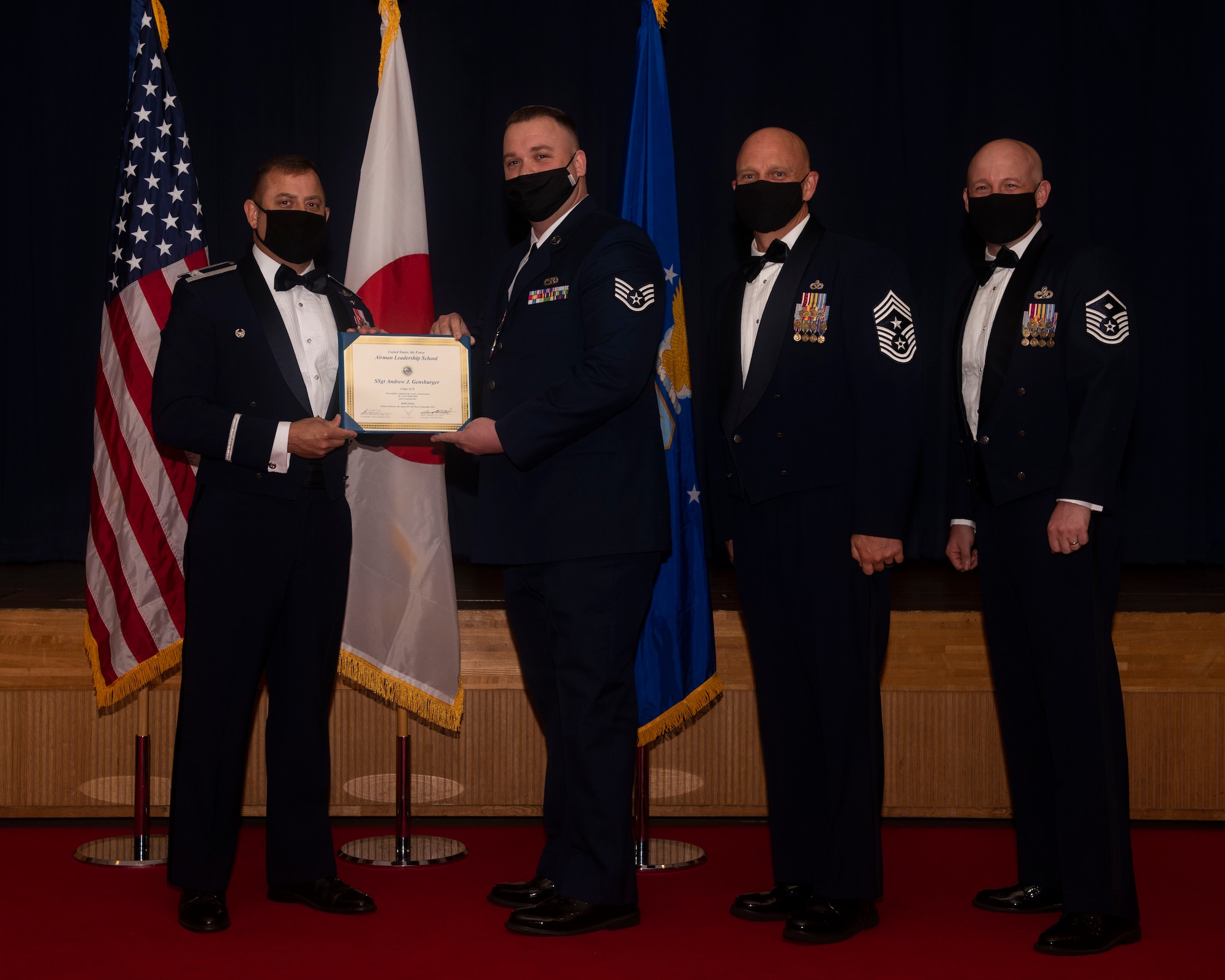 Military members in uniform pose with a diploma for a photo