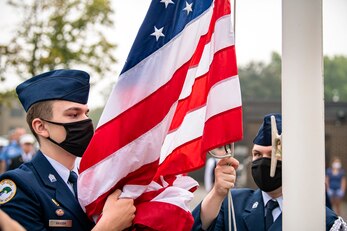 A cadet from the Alconbury Middle Highschool JROTC catches the flag during a 9/11 remembrance ceremony at RAF Alconbury, England, Sept. 9, 2021. Cadets, Airmen from the 501st Combat Support Wing and guests came together to pay homage to those who lost their lives during the Sept. 11, 2001, attacks. (U.S. Air Force photo by Senior Airman Eugene Oliver)