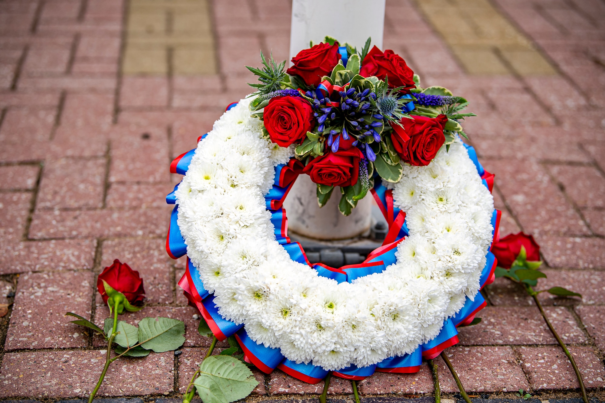 A Wreath rests on a flagpole during a 9/11 Remembrance ceremony at RAF Alconbury, England, Sept. 9, 2021.  Airmen from the 501st Combat Support Wing, cadets from the Alconbury Middle Highschool JROTC and guests came together to pay homage to those who lost their lives during the Sept. 11, 2001, attacks. (U.S. Air Force photo by Senior Airman Eugene Oliver)