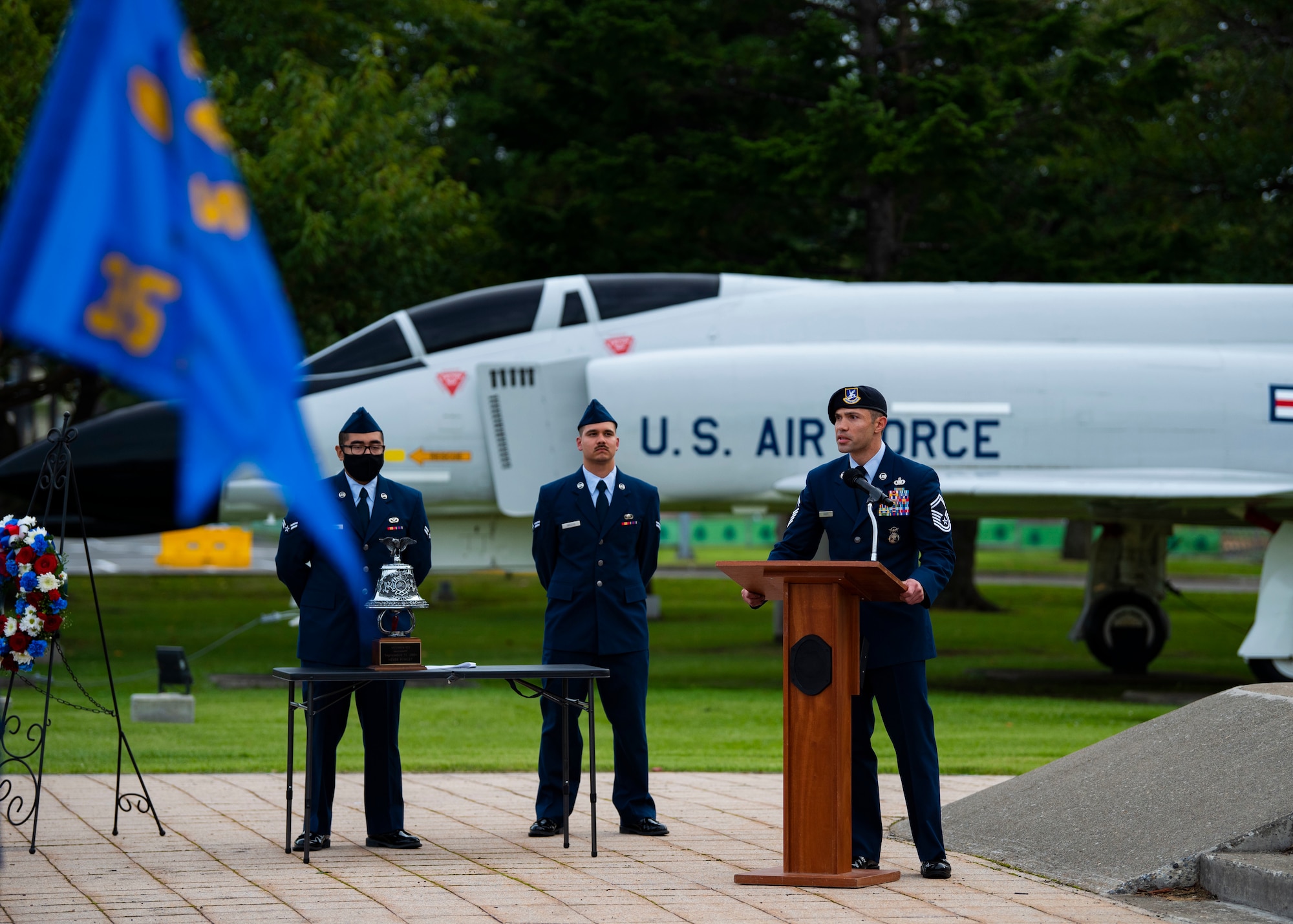 Military member in uniform gives a speech at a podium.