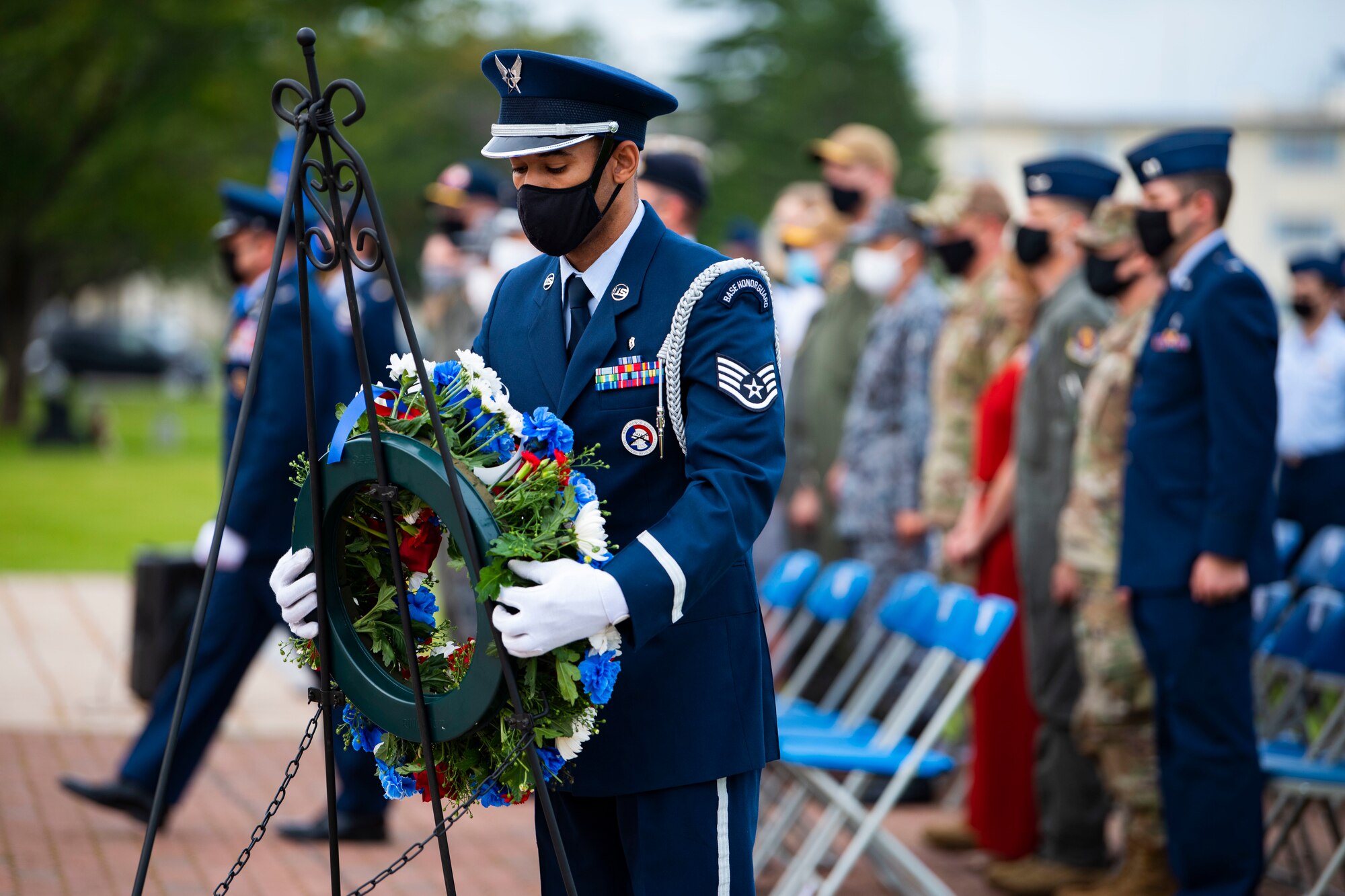 Military member in uniform picks up a wreath.