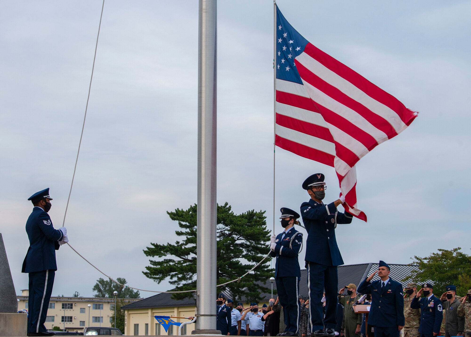 Military members in uniform lower an American flag.