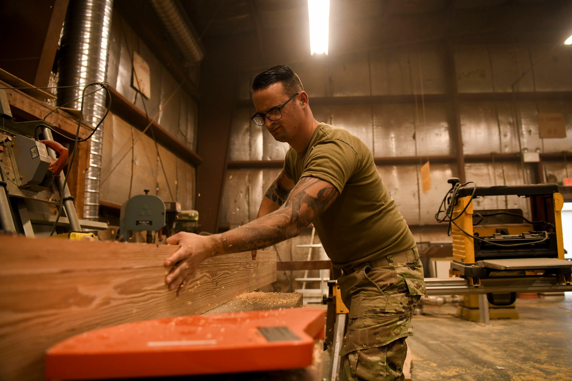 U.S. Air Force Staff Sgt. William Criswell, 8th Civil Engineer Squadron noncommissioned officer in charge of the lock shop, runs wood plank through a sanding machine at Kunsan Air Base, Republic of Korea, Aug 28, 2021. Volunteers from across the Wolf Pack dedicated hours of woodworking, gardening, painting and more to ensure the Kunsan Air Base Legacy Garden was built and dedicated to veterans by Sept 8, 2021. (U.S. Air Force photo by Staff Sgt. Jesenia Landaverde)