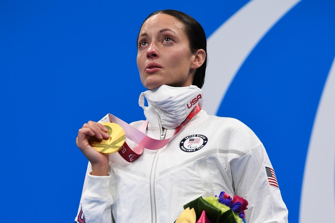 An athlete has tears in her eyes as she hold a gold medal in her hands.