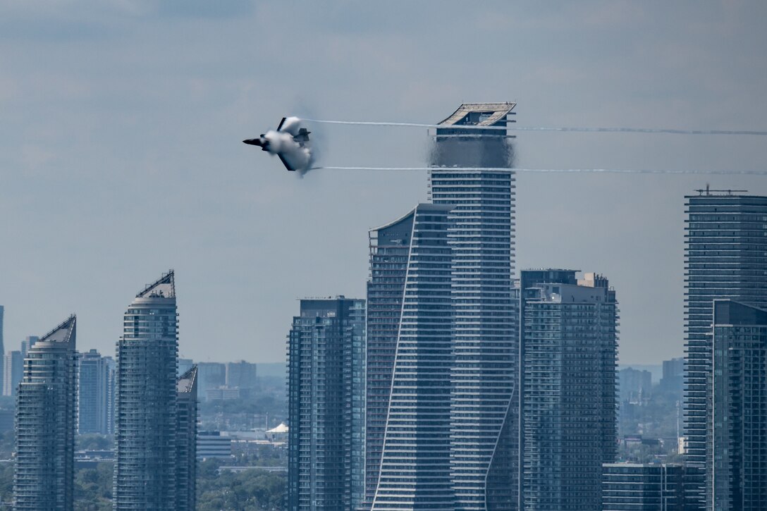 An F-35 jet soars above high-rise buildings.