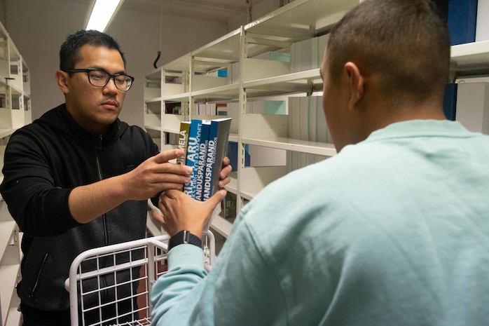 (Sept. 6, 2021) Machinist Mate 3rd Class Tai Tran, left, and Quartermaster 3rd Class Carlos Paredes, assigned to the Arleigh Burke-class guided-missile destroyer USS Arleigh Burke (DDG 51) organize books during a community relations event at the National Library of Estonia while the ship is in port in Tallinn, Estonia, Sept. 6, 2021. Arleigh Burke, forward-deployed to Rota, Spain, is on its first patrol in the U.S. Sixth Fleet area of operations in support of U.S. national security interests and regional allies and partners in Europe and Africa.