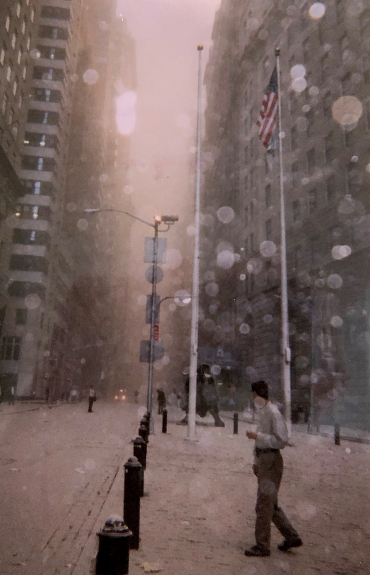 People walk in a dust and debris-filled street after the collapse of the first Twin Tower and look towards the fire coming from the second on Sept. 11, 2001, in front of the World Trade Center, New York City, New York. Col. Ephod Shang, vice commander of the 367th Recruiting Group and deputy director at the AFRC Headquarters for Recruiting on Robins AFB, Georgia, and others were hiding behind a random structure when the first tower fell, the dust completely blocked their vision. (Courtesy photo by Col. Ephod Shang)