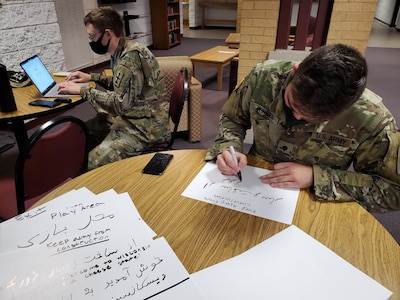 U.S. Army Cpl. Sean Jackett, left, and Spc. Zackary Jensen, Wisconsin Army National Guard linguists, create signs in Dari and Pashto, Aug. 25, 2021, to place in a welcome area for Afghan people arriving at Volk Field Combat Readiness Training Center near Camp Douglas, Wisconsin.