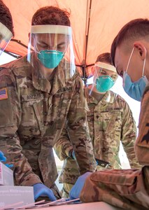 Spc. Kenneth Bentzler, left, a motor transport operator for 1157th Transportation Company, and Spc. Nash Brickl, right, an ammunition specialist for 641st Troop Command Battalion assigned to Task Force McCoy, prepare to conduct COVID-19 testing Sept. 7, 2021, at Fort McCoy, Wisconsin, as part of Operation Allies Welcome.