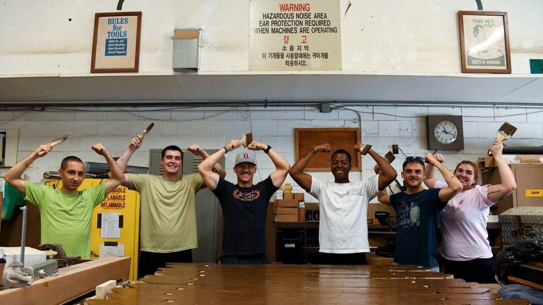 U.S. Air Force Airmen from the 80th Aircraft Maintenance Unit, break into the unit’s signature pose at Kunsan Air Base, Republic of Korea, Aug 28, 2021. Volunteers from across the Wolf Pack dedicated hours of woodworking, gardening, painting and more to ensure the Kunsan Air Base Legacy Garden was built and dedicated to veterans by Sept 8, 2021. (U.S. Air Force photo by Staff Sgt. Jesenia Landaverde)