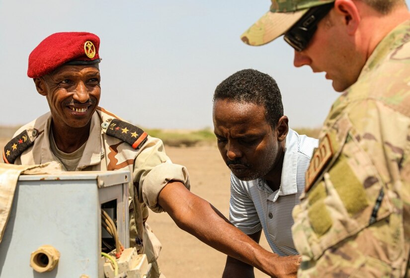 A soldier from Djibouti works on a piece of machinery with an American soldier.