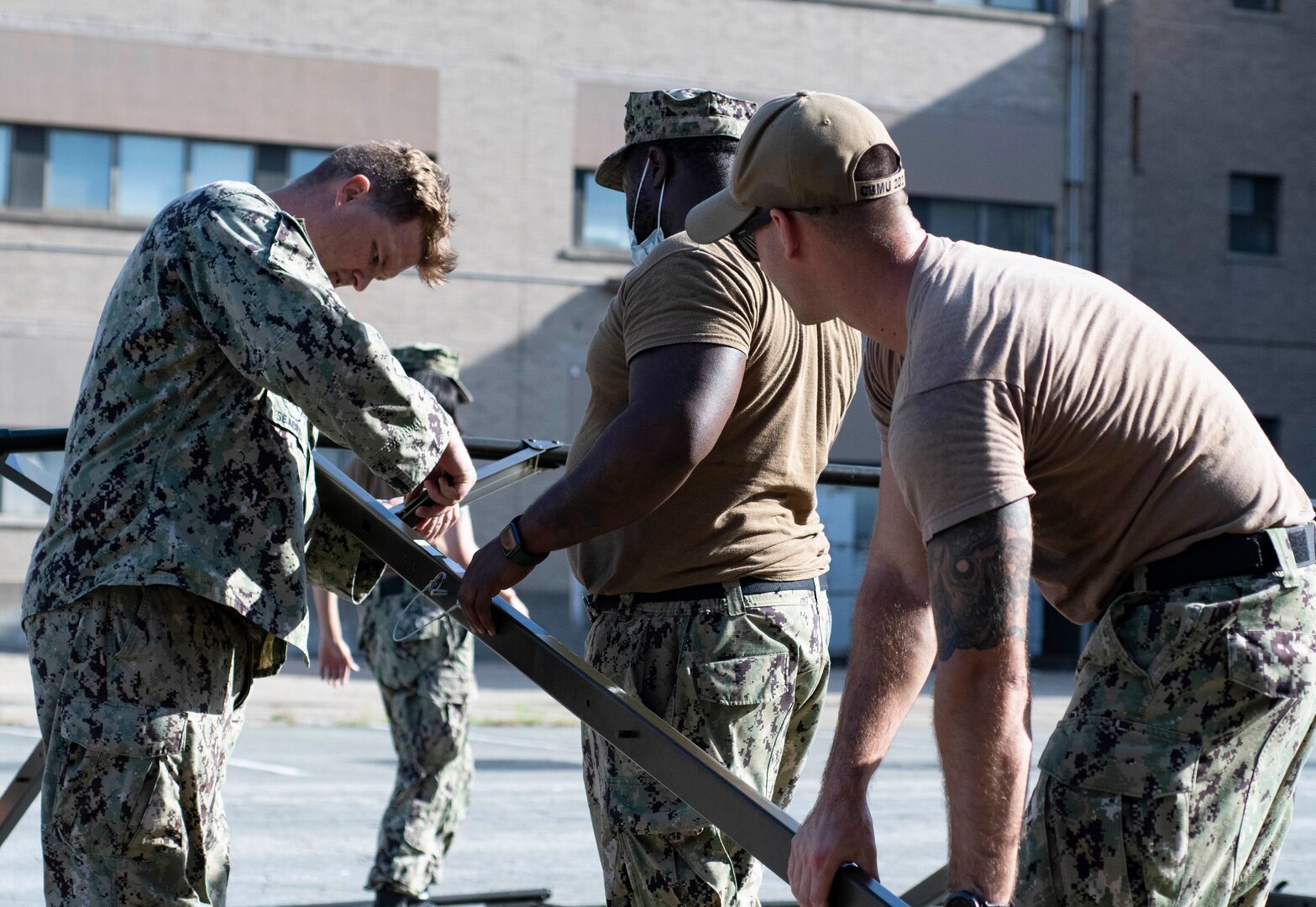 Sailors assigned to Construction Battalion Maintenance Unit Two Zero Two (CBM 202) construct a tent at Naval Medical Center Portsmouth (NMCP), Aug. 31.