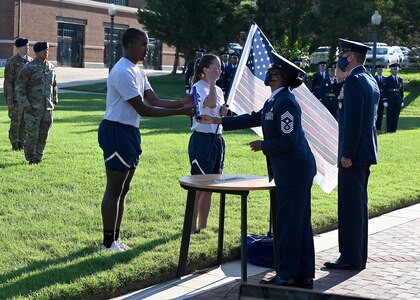 The 11th Wing and Joint Base Anacostia-Bolling Command Team, Command Chief Master Sgt. Christy Peterson and Col. Mike Zuhlsdorf, hand a ceremonial baton and flag to Staff. Sgt. Bryan Potter, 794th Communication Squadron, and 1st Lt. Hillary Bissing, 11th Logistics Readiness Squadron, before they lead a 9/11 memorial run on Sept. 10, 2021. Mission  partners from across the National Capitol Region gathered at JB Anacostia-Bolling to honor those who died 20 years ago during the terror attacks on the World Trade Center and the Pentagon on September 11, 2001. (U.S. Air Force photo by Staff Sgt. Kayla White)