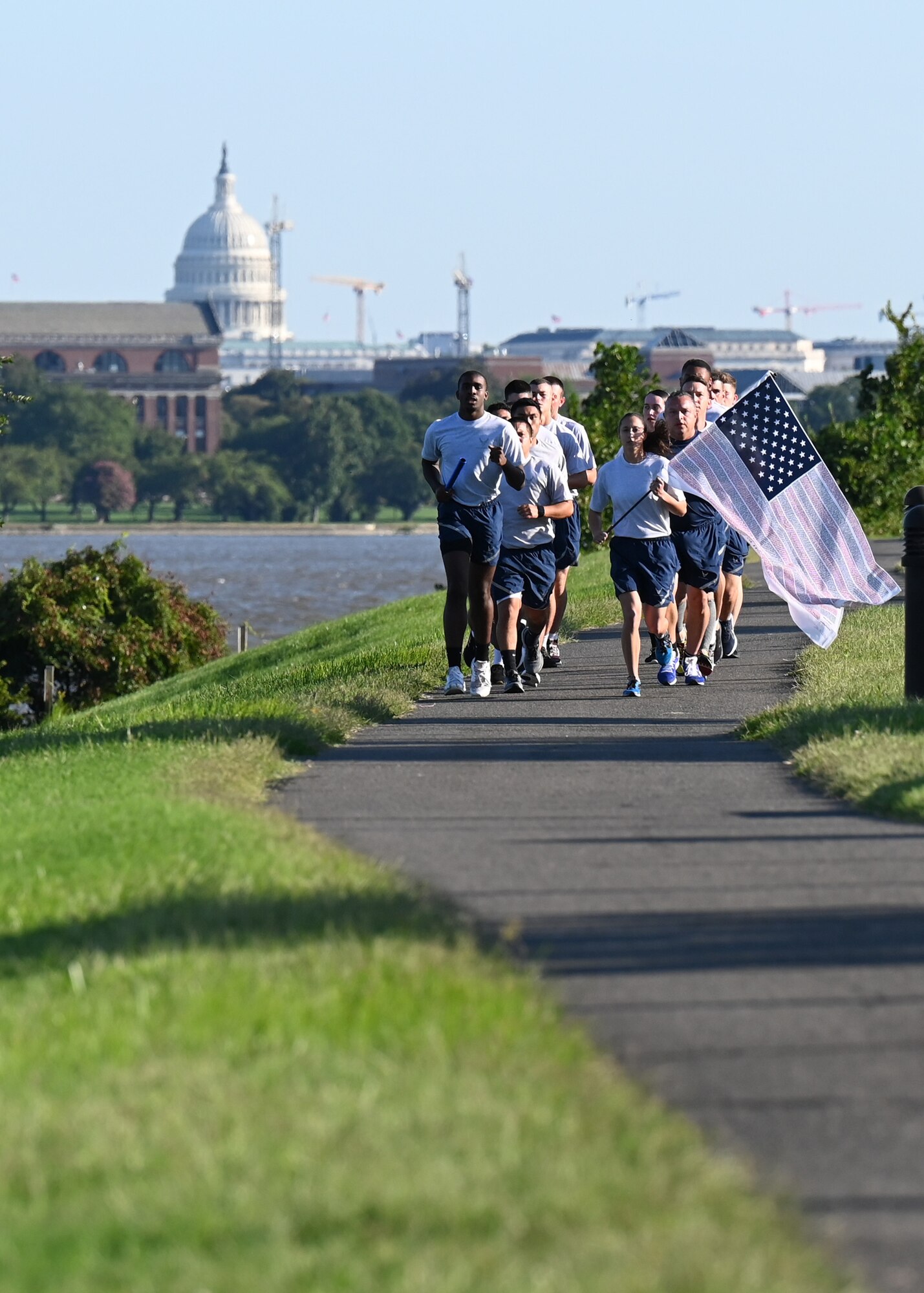 U.S. Air Force Staff. Sgt. Bryan Potter, 794th Communication Squadron, and 1st Lt. Hillary Bissing, 11th Logistics Readiness Squadron, carry a ceremonial baton and flag during a 9/11 memorial run along the Potomac River at Joint Base Anacostia-Bolling, Washington D.C. on Sept. 10, 2021. Mission partners from across the National Capitol Region gathered at JB Anacostia-Bolling to honor those who died 20 years ago during the terror attacks on the World Trade Center and the Pentagon on September 11, 2001. (U.S. Air Force photo by Staff Sgt. Kayla White)