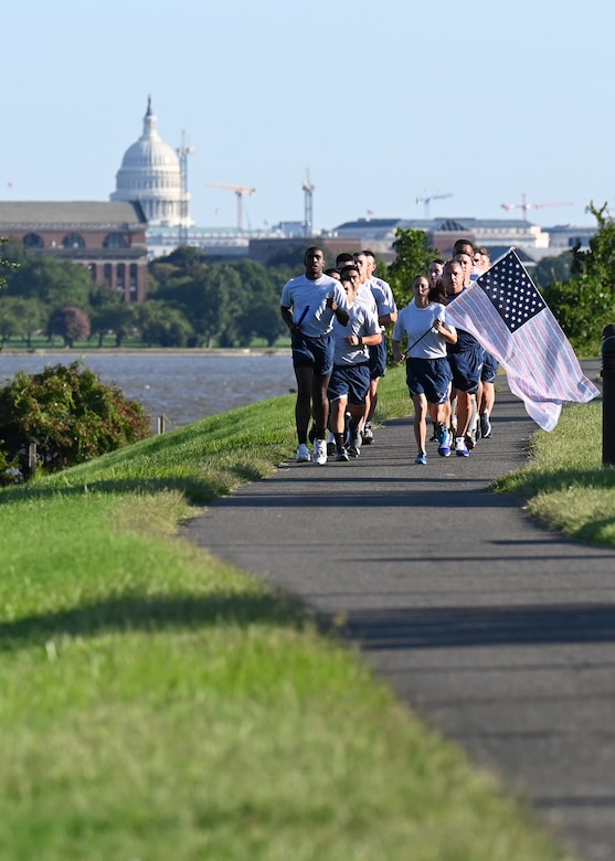 U.S. Air Force Staff. Sgt. Bryan Potter, 794th Communication Squadron, and 1st Lt. Hillary Bissing, 11th Logistics Readiness Squadron, carry a ceremonial baton and flag during a 9/11 memorial run along the Potomac River at Joint Base Anacostia-Bolling, Washington D.C. on Sept. 10, 2021. Mission partners from across the National Capitol Region gathered at JB Anacostia-Bolling to honor those who died 20 years ago during the terror attacks on the World Trade Center and the Pentagon on September 11, 2001. (U.S. Air Force photo by Staff Sgt. Kayla White)