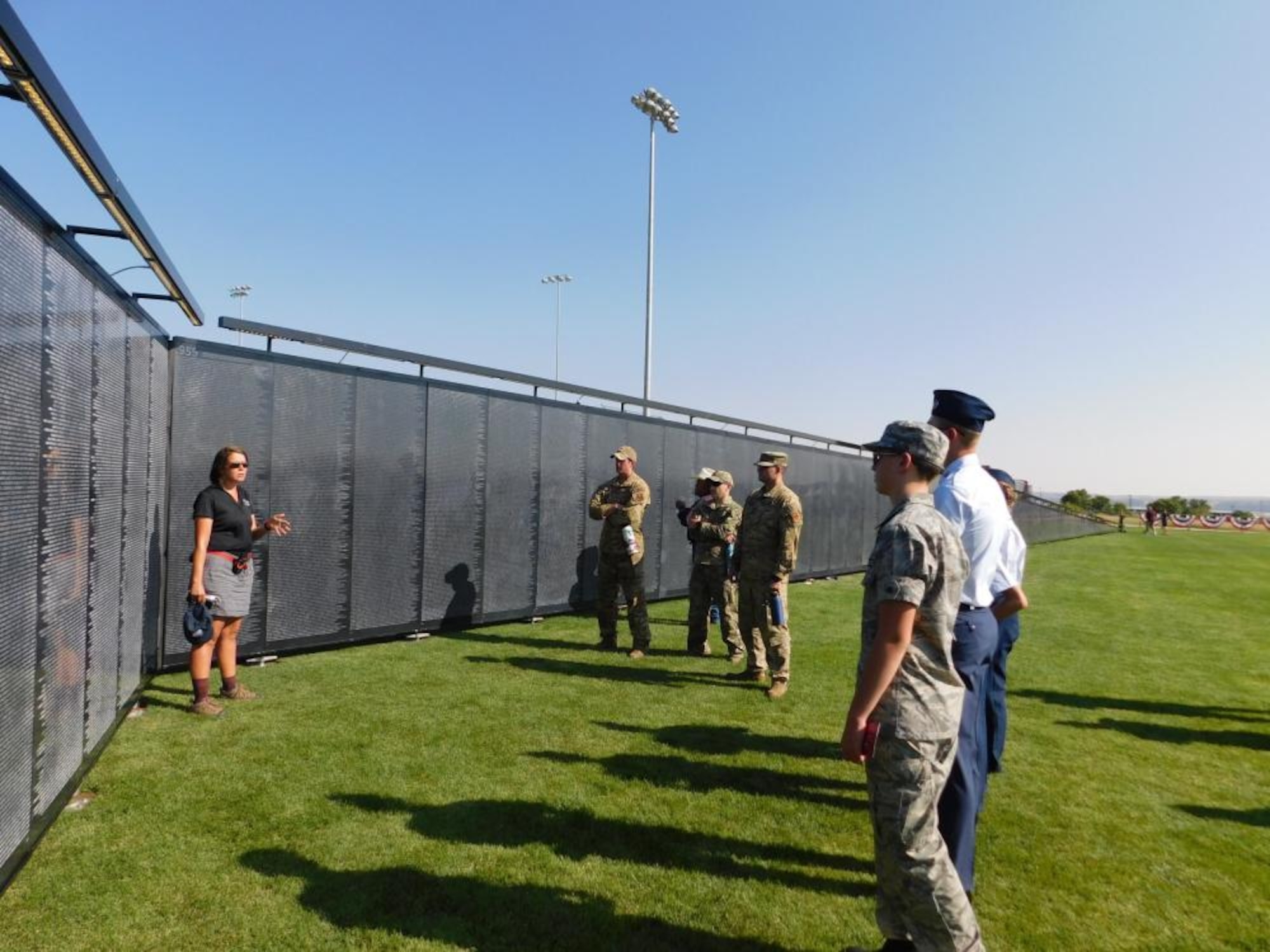 A civilian woman speaks to Airmen and cadets at a replica of the Vietnam memorial Wall.