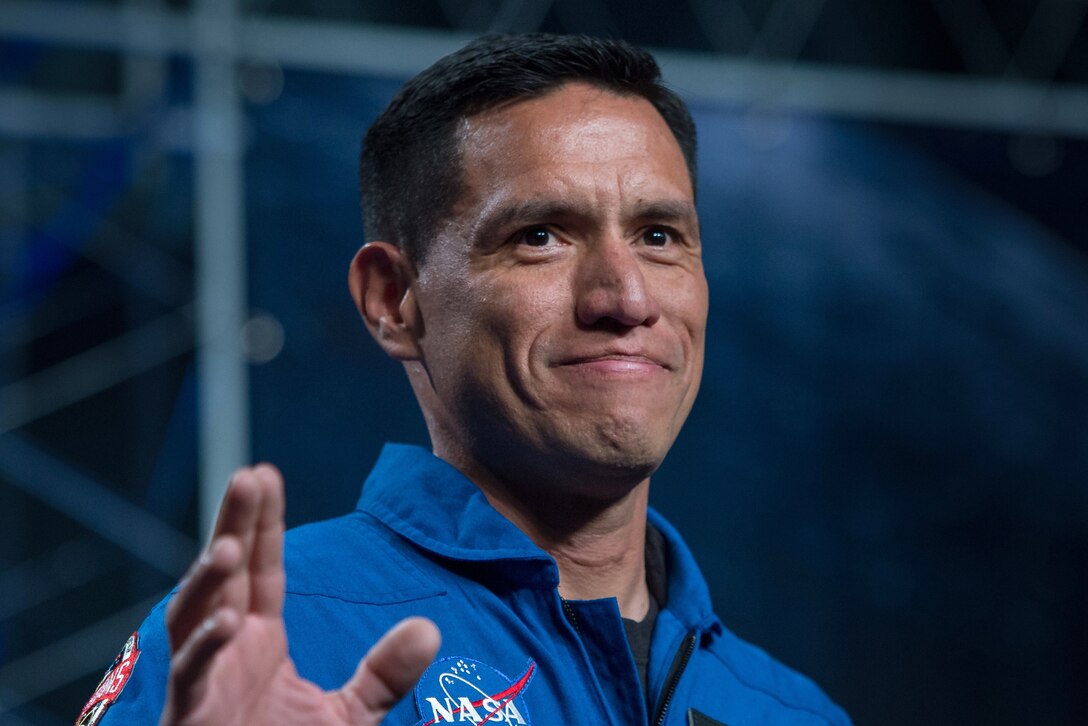 A man in a NASA uniform waves.